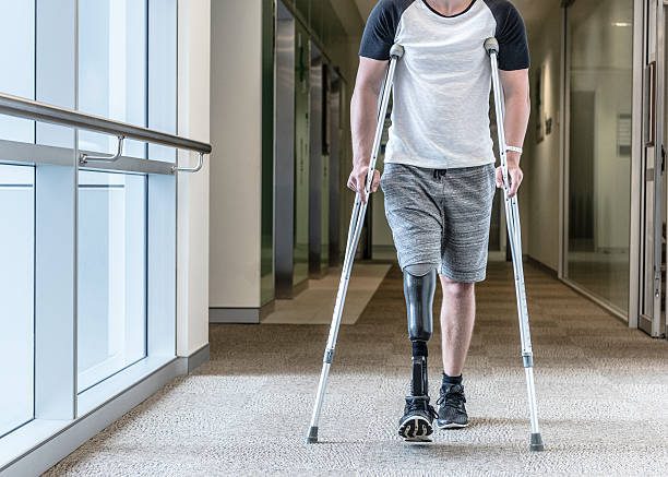 Man with prosthetic leg using crutches in hallway.